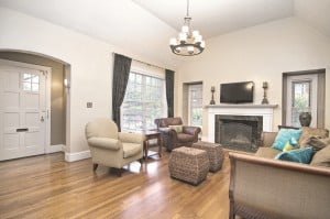 Living room with beige walls large white front door fireplace with white mantle and wood floors