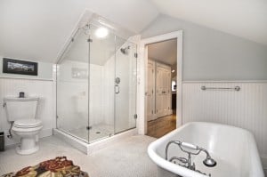 Bathroom with light blue walls white chair molding halfway up wall white tile floors white clawfoot tub white subway tile walk in shower with glass door