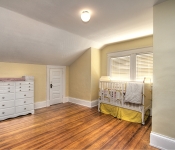 Bedroom with yellow walls white baseboards wood floors white changing table white crib with white and yellow bedding
