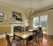 Dining room with yellow walls white chair molding and white baseboards green and yellow tile fireplace with white mantle