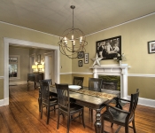 Dining room with yellow walls white chair molding and white baseboards green and yellow tile fireplace with white mantle