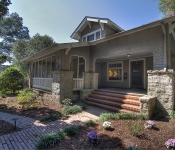 Home with gray shingles stone details around columns screened in front porch brick steps and walkway