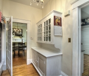 Hallway with beige walls wood floors white door entry to kitchen and dining room black chalkboard walls white built in cabinets