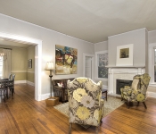 Living room with light gray walls white baseboards wood floors white painted brick fireplace with white mantle windows around fireplace