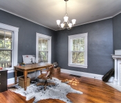 Home office with blue walls large white framed windows and white baseboards wood floors and white painted brick fireplace with white mantle