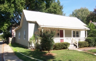 Siding home with red front door white trim windows front porch with white railing and white columns