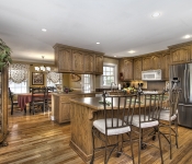 Kitchen with wood cabinets brown countertops window over sink white appliances recessed lighting brown walls with white chair molding and baseboards wood floors