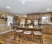 Kitchen with wood cabinets brown countertops window over sink white appliances recessed lighting brown walls with white chair molding and baseboards wood floors