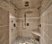 Large walk in tile shower with brown tile walls ceiling and floors