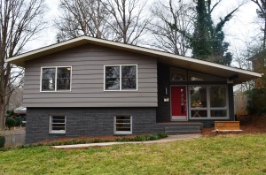 Gray siding and painted brick split level home with gray and white framed windows red front door