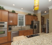 Kitchen with brown cabinets brown granite countertops brown tile backsplash stainless steel appliances light brown walls