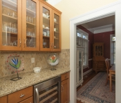 Bar area in kitchen with wood cabinets and brown granite countertop and brown tile backsplash built in wine fridge
