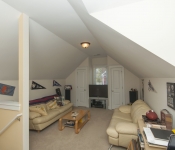 Room with white walls low vaulted ceiling carpet flooring yellow leather sofas