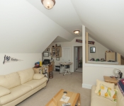Room with white walls low vaulted ceiling carpet flooring yellow leather sofas