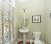 Bathroom with light green walls white baseboards white toilet white pedestal sink window with white and light brown blinds