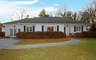 White siding home with black shutters black front door black ceiling roof green grass front yard
