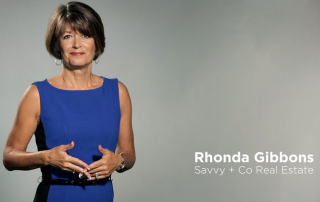 Rhonda Gibbons wearing a blue and black sleeveless dress standing in front of gray backdrop