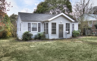 Home with light gray siding black shutters black front door black shingle roof mailbox right by front door grass in front yard