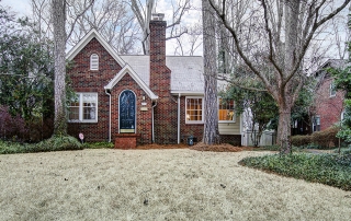 Red brick home with chimney white framed windows black arched front door with brick steps up to it