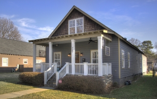 Two story home with blue siding and brown shingles front porch with white columns and railings black ceiling fans