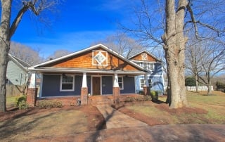 Home with blue siding large red brick front porch wood front door wood shingle details