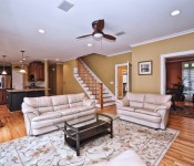 Living room with wood floors white trim yellow walls wood ceiling fan with white leather sofas and open to kitchen