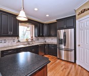 Kitchen with black cabinets stainless steel appliance wood floors black granite countertops tile backsplash