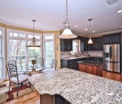 Kitchen with half black cabinets and half brown cabinets stainless steel appliance wood floors gray granite countertops and black granite countertops