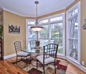 Eating area with yellow walls large floor to ceiling windows looking into back yard wood floors