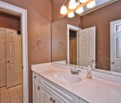 Bathroom with brown walls white cabinets white countertops white tile floors