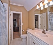 Brown walls white tile floors white cabinets white countertops white toilet blue and white shower curtain