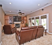 Room with brown walls windows with brown shades brown pattern carpet brown leather reclining chairs built in wood bookshelves