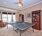 Room with brown walls recessed lighting ceiling fan windows with brown shades brown carpet and ping pong table