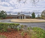 Neighborhood clubhouse with large circular driveway and American flag on flagpole