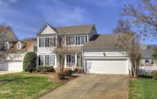 Two story white siding home with white two car garage door black shutters small front porch with white railing and columns