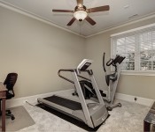 Home gym with light brow walls white baseboards window with white trim dark brown ceiling fan