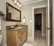 Bathroom with light brown cabinets brown granite countertop dark wood framed mirror