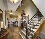 Foyer with dark wood floors light brown walls white molding stairs with iron railing wood steps double dark wood front doors