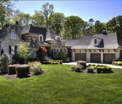 Front of large three story brick and stone home with three car garage and manicured front lawn