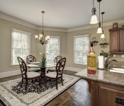 Eating area in kitchen with light brown walls dark wood floors windows on walls small chandelier over table