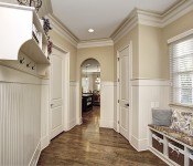 Hallway with light brown walls chair molding dark wood floors arched entryway to kitchen built in bench with cubbies under window