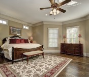 Master bedroom with light brown walls white trim dark wood ceiling fan dark wood floors windows and door to backyard