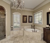 Bathroom with round white soaking tub surrounded by tile with the same tile on the floor and. in the walk in shower glass shower door dark wood cabinets