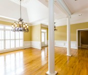 Empty living room with wood floors yellow walls white chair molding large windows and door to backyard white columns