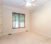 Empty room with white walls white baseboards white ceiling fan white carpet white double doors with gold door handles