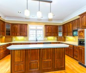 Kitchen with dark wood cabinets wood floors yellow walls white countertops black appliances window over sink wood floors