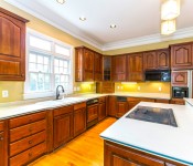 Kitchen with dark wood cabinets wood floors yellow walls white countertops black appliances window over sink