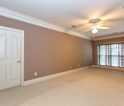 Large room with brown walls white carpet white trim white ceiling fan