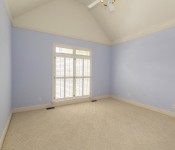 Empty bedroom with light blue walls vaulted ceiling white ceiling fan white baseboards
