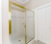 Shower with gold frame glass door tile walls and floors